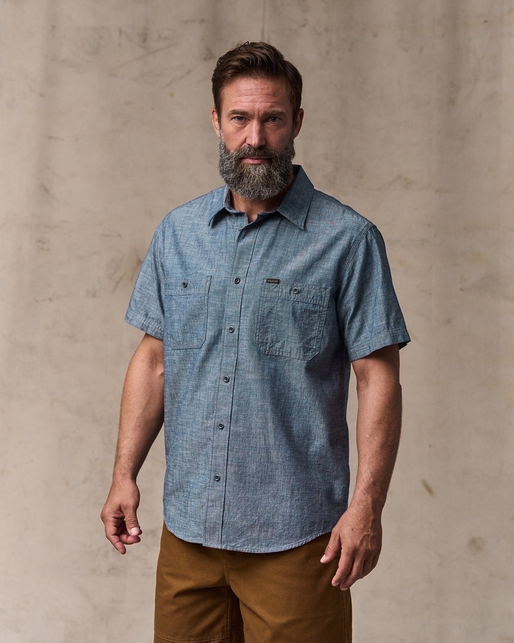 image of a model wearing Filson's Short-sleeve Embroidered Chambray Shirt - Rinsed Indigo
