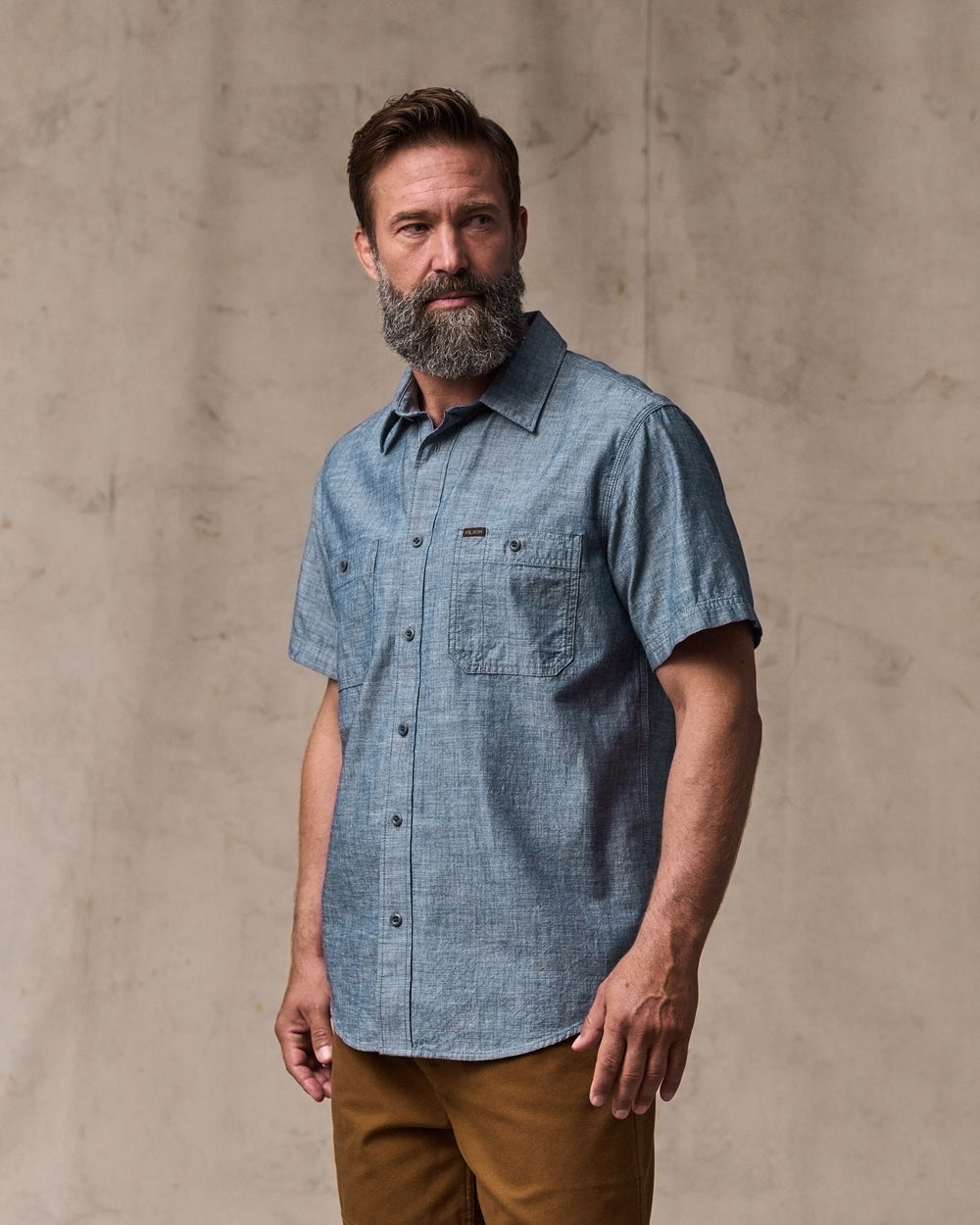 image of a model wearing Filson's Short-sleeve Embroidered Chambray Shirt - Rinsed Indigo